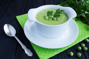 Pea soup in the white bowl on the black wooden background.Closeup.