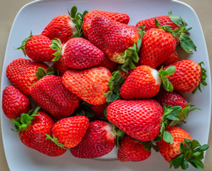 Group of ripe and juicy strawberries ready to eat, placed on a white plate