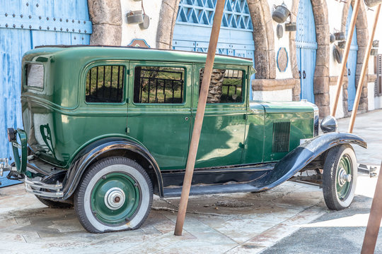 Antique green car with a punctured rear wheel