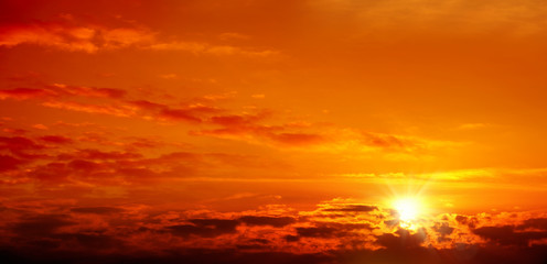 Beautiful cloudscape of orange colored sunset sky with shining sun