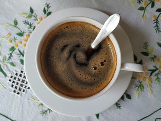 A closeup coffee cup on the table at noon.