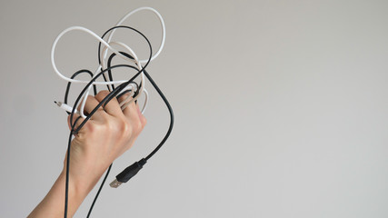 Black and white cables in a left woman's hand on a light gray background