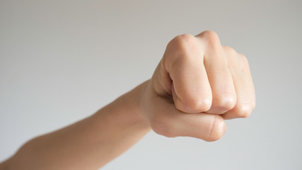 Woman's fist isolated on a light gray background. Close up to the camera. Front view.