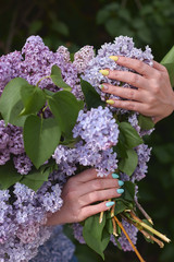 young girl in blue jeans holding a large bouquet of lilacs