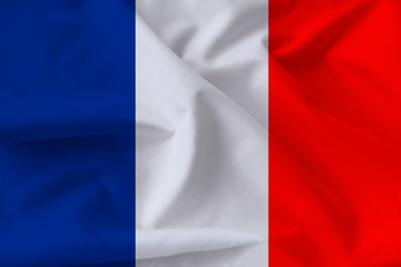 beautiful national flag of France on soft silk with soft folds in the wind, close-up, copy space