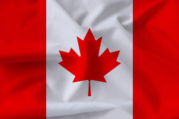 beautiful national flag of Canada on soft silk with soft folds, close-up, copy space