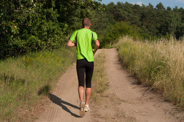Dynamic running uphill on trail male athlete runner back view