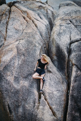 blonde girl sitting on a rock formation by the beach in Thailand