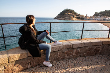 Woman watching at medieval fortress on coast near mediterranean town