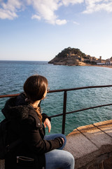 Fototapeta premium Woman watching at medieval fortress on coast near mediterranean town