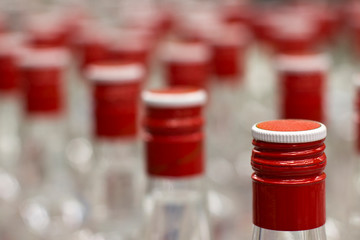 bottles of vodka with red caps on the conveyor of the plant for the production of alcohol