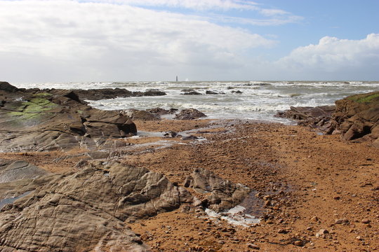Les Sables-d'Olonne : anse de la Paracou &agrave; mar&eacute;e basse (rochers et phare des Barges au loin)