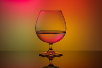 One glass on the table on a multi-colored background