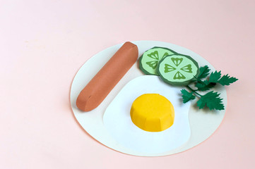 Paper fried eggs with sausage, cucumber slices and parsley on plate