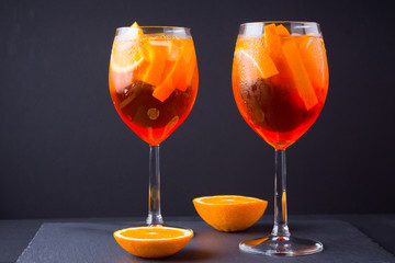 Cocktail aperol spritz on black background. Summer alcohol cocktail with orange fruit and fresh mint. Italian cocktail aperol spritz on wooden boards
