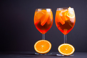 Cocktail aperol spritz on black background. Summer alcohol cocktail with orange fruit and fresh mint. Italian cocktail aperol spritz on wooden boards