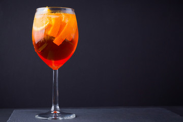 Cocktail aperol spritz on black background. Summer alcohol cocktail with orange fruit and fresh mint. Italian cocktail aperol spritz on wooden boards