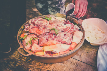 woman hand pours fresh meat with red wine