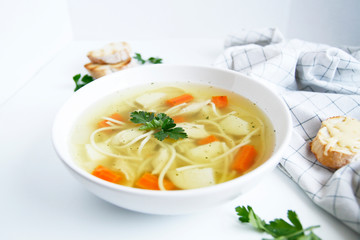 Russian chicken soup with carrots, potatoes, noodles on a light background. view top