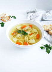 Russian chicken soup with carrots, potatoes, noodles on a light background. view top