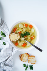 Russian chicken soup with carrots, potatoes, noodles on a light background. view top