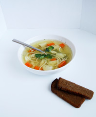 Russian chicken soup with carrots, potatoes, noodles on a light background. view top
