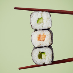 Three maki sushi rolls displayed with chopsticks © exclusive-design