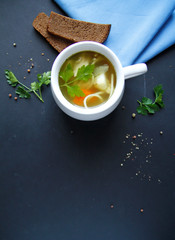 Russian chicken soup in a white dish with carrots, potatoes, vermicelli on a black background. top view. with black bread