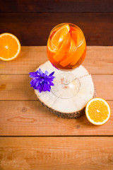 Cocktail aperol spritz on wooden boards. Summer alcoholic cocktail with orange slices and flowers. Aperol spritz on wooden boards