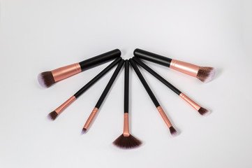 Set of professional makeup brushes with purple tips and black and golden handels isolated on white background. Makeup brushes for blush, eyeshadows, powder, foundation to blend cosmetic products