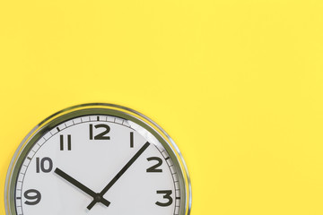 Part of analogue plain wall clock on trendy yellow background. Ten o'clock. Close up with copy...