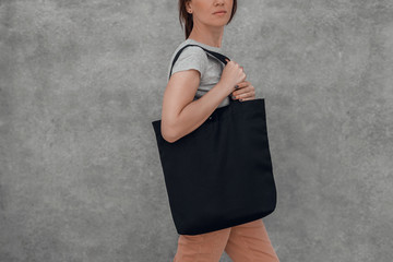 Young woman with black cotton bag in her hands. Mock up.
