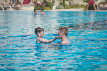 Conscious parenting. Father is teaching his son to swim at the hotel’s pool. - 274124210