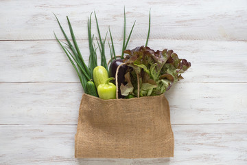 Vegetables in a grocery bag on a wooden table