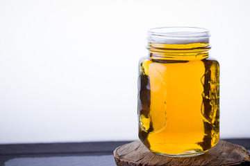 Beer with foam in mason jar on a white background. A glass of light beer on a wooden stand. Low alcohol drink on slate board. Copy space