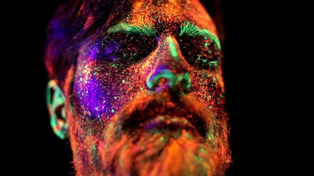 Concept. Portrait of a bearded man. The man is painted in ultraviolet powder