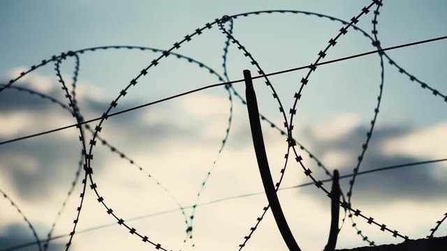 A fence with barbed wire against the sky. Close-up. Security systems Restricted area. Restriction of human freedom