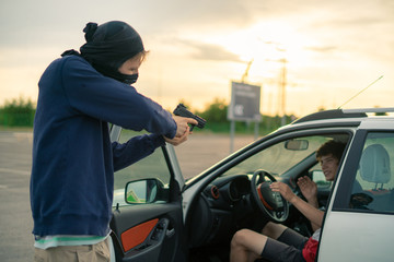 criminal accident, burglar threatening the car driver with a pistol on the parking