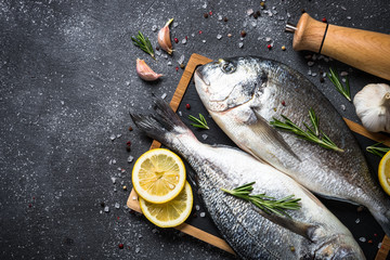 Raw dorado fish on black background.