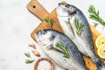Raw dorado fish on cutting board on the table.