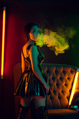 Sexy brunette model is smoking a hookah exhaling a smoke at a luxury night club.