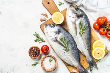 Raw dorado fish on cutting board on the table.