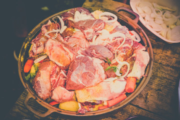 Fresh meat with vegetables prepared for baking, on a wooden table