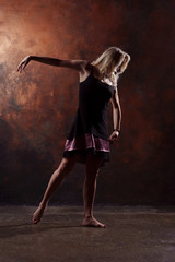 Fototapeta na wymiar Full-length photo of dancing blonde in short black dress on brown background