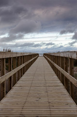 Fototapeta premium wooden footbridge over the beach in cloudy winter day