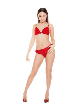 Young woman in red lingerie full length standing on white background