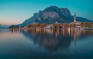 The city of Lecco on Lake Como with reflections in the water during a blue hour in an autumn day