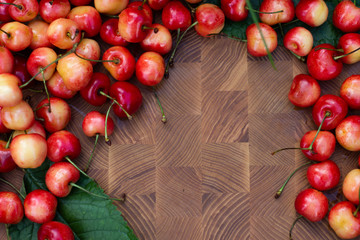 Yellow sweet cherry in on a wooden cutting board on a background of green grass. Close-up. Copy space.
