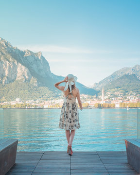 A girl with a straw hat looking at the city of Lecco on Lake Como