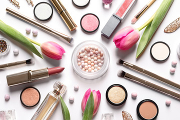 Different makeup products and flowers on white background, top view